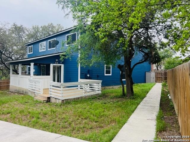 exterior space with a front yard, fence, and a wooden deck