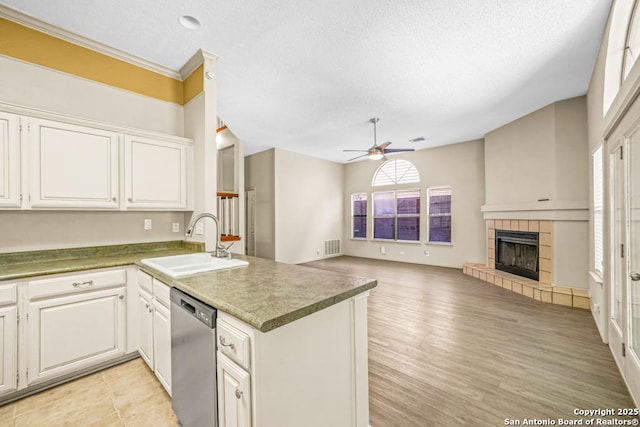 15338 Winter Mist Dr, San Antonio, TX 78247 - kitchen featuring stainless steel dishwasher, a peninsula, a ceiling fan, a sink, and a tile fireplace