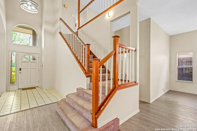 15338 Winter Mist Dr, San Antonio, TX 78247 - foyer with a textured ceiling, a towering ceiling, visible vents, stairway, and wood finished floors