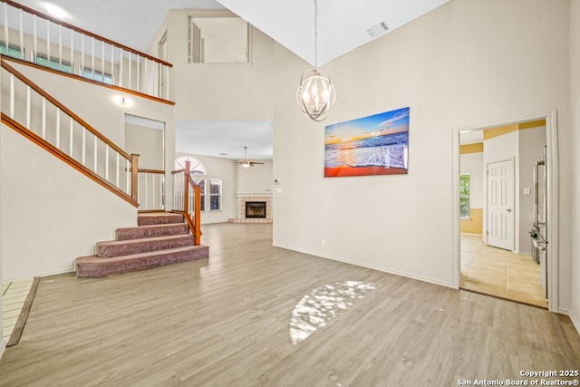 15338 Winter Mist Dr, San Antonio, TX 78247 - unfurnished living room featuring plenty of natural light, a fireplace, stairway, visible vents, and wood finished floors