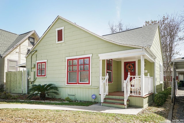 bungalow-style home featuring a porch, fence, and a shingled roof