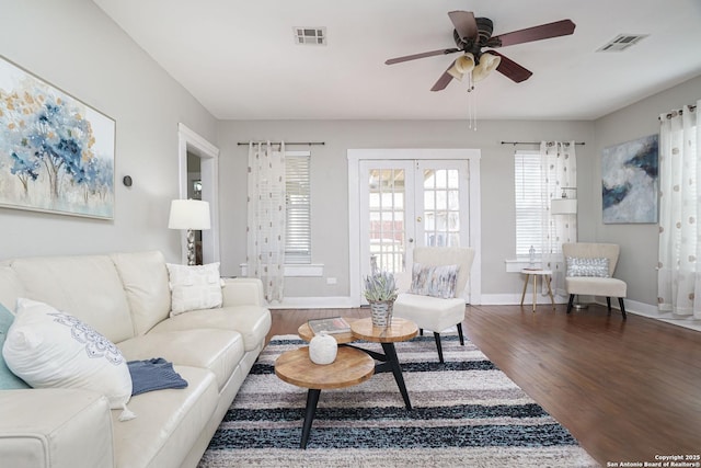 living room featuring wood finished floors, ceiling fan, baseboards, and visible vents