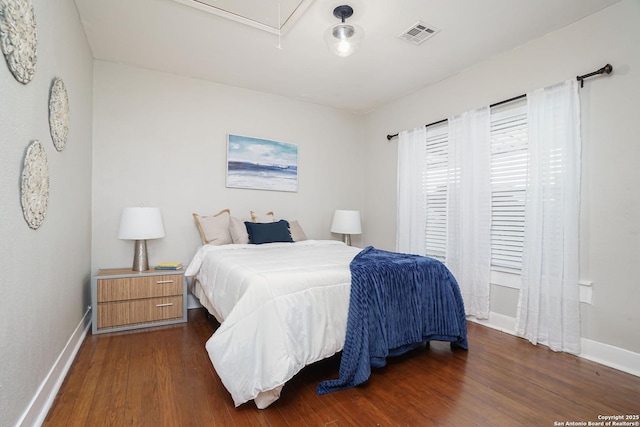 bedroom featuring attic access, dark wood-style flooring, baseboards, and visible vents