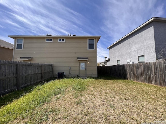 rear view of house with a yard, a fenced backyard, and central AC unit