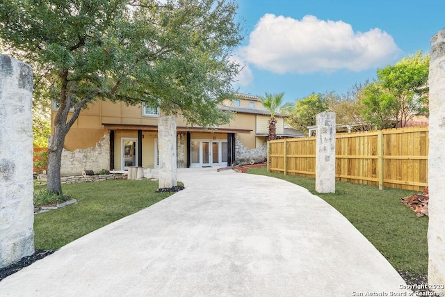 4935 Driskill St, San Antonio, TX 78228 - view of front of house featuring french doors, a front lawn, fence, and stone siding