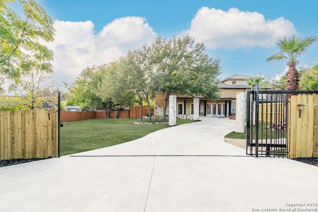 4935 Driskill St, San Antonio, TX 78228 - view of front of home featuring stucco siding, a front yard, stone siding, fence, and a gate