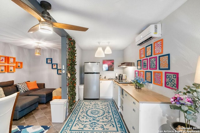 4935 Driskill St, San Antonio, TX 78228 - kitchen with white cabinets, an AC wall unit, light countertops, freestanding refrigerator, and a ceiling fan