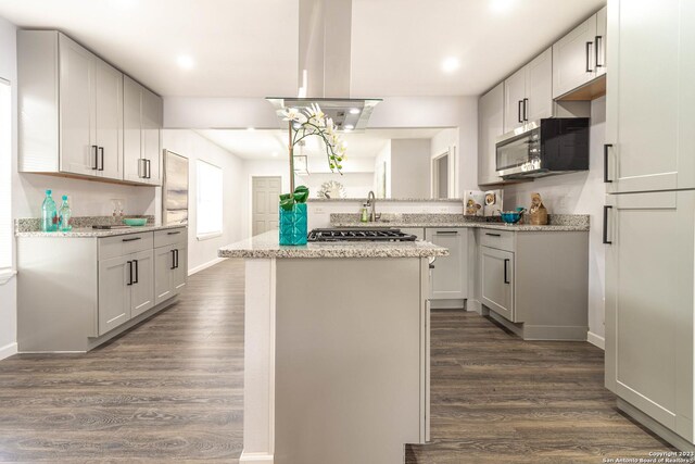 1209 Kentucky Ave, San Antonio, TX 78201 - kitchen featuring baseboards, island exhaust hood, stainless steel microwave, light stone countertops, and dark wood-type flooring