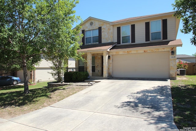 traditional-style house with central AC unit, an attached garage, stone siding, fence, and driveway