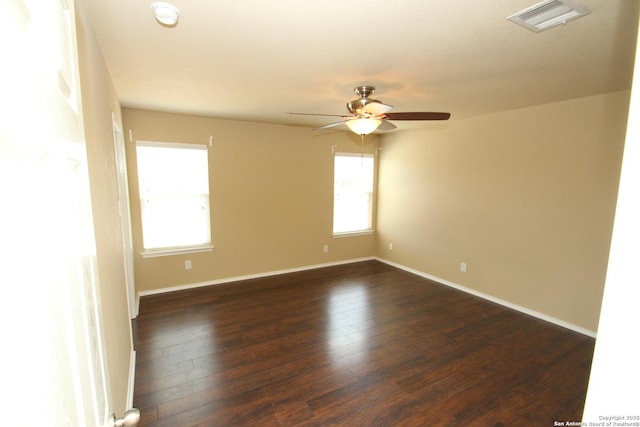 unfurnished room featuring visible vents, baseboards, a ceiling fan, and dark wood-style floors