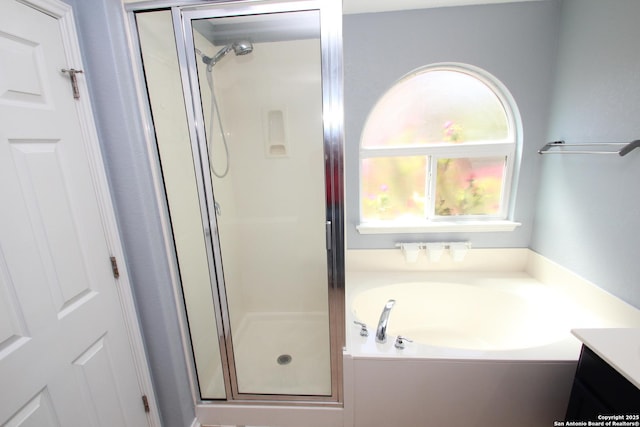 full bathroom featuring a shower stall, a bath, and vanity