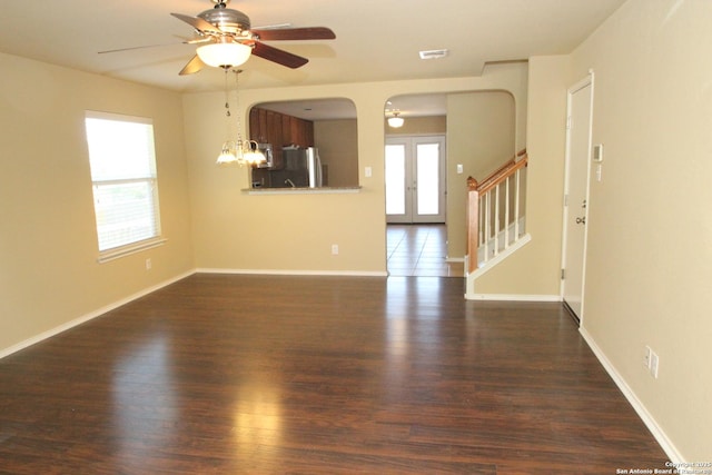 unfurnished living room featuring dark wood-style flooring, baseboards, stairway, visible vents, and ceiling fan