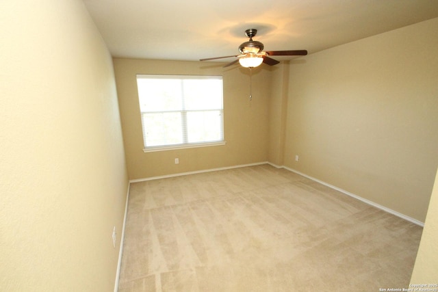spare room featuring baseboards, light colored carpet, and a ceiling fan