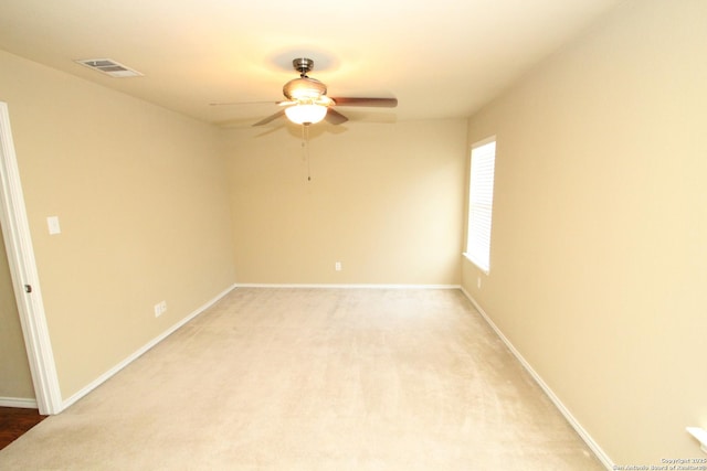 empty room featuring light colored carpet, baseboards, a ceiling fan, and visible vents
