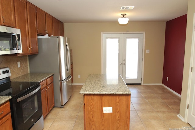 kitchen featuring french doors, a kitchen island, visible vents, decorative backsplash, and stainless steel appliances