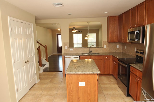kitchen featuring visible vents, a center island, a sink, stainless steel appliances, and backsplash