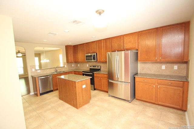kitchen featuring a kitchen island, visible vents, appliances with stainless steel finishes, arched walkways, and a sink