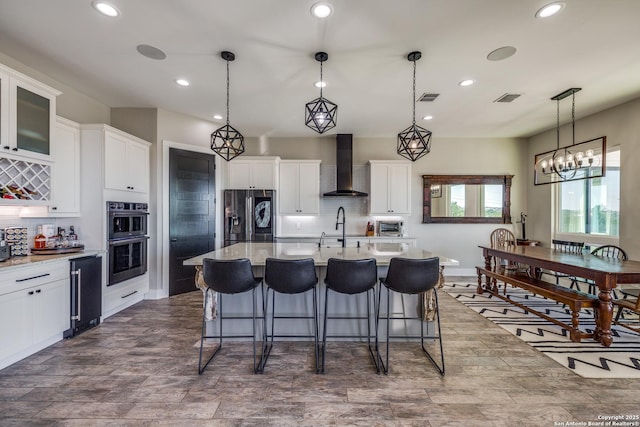 112 Chinkapin, Boerne, TX 78006 - kitchen featuring wall chimney range hood, stainless steel appliances, visible vents, and a breakfast bar
