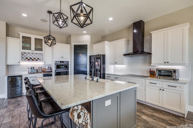 112 Chinkapin, Boerne, TX 78006 - kitchen featuring wall chimney exhaust hood, dark wood-type flooring, black appliances, a large island, and beverage cooler