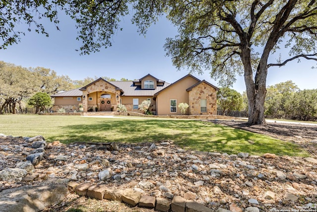 view of front facade with metal roof, stucco siding, stone siding, and a front lawn