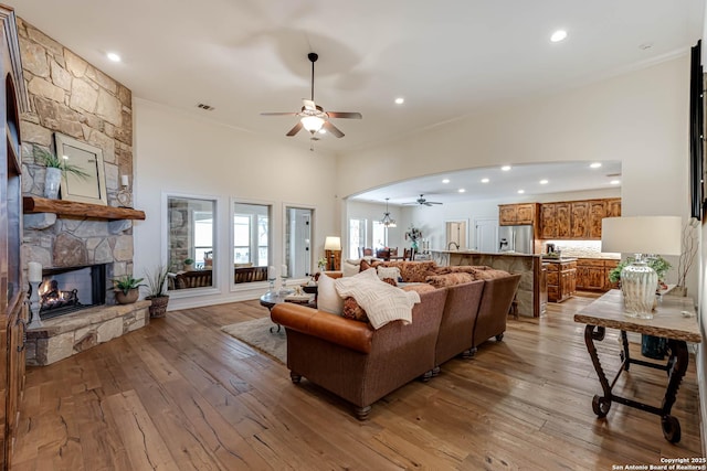 living area featuring recessed lighting, light wood-style flooring, a stone fireplace, and ceiling fan