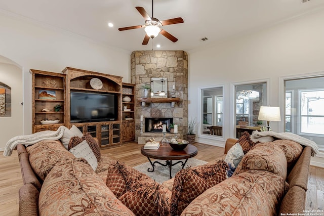 living area with ornamental molding, light wood-style flooring, a ceiling fan, and a high ceiling