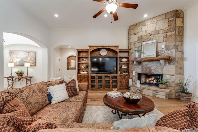 living room with crown molding, a ceiling fan, arched walkways, and wood finished floors