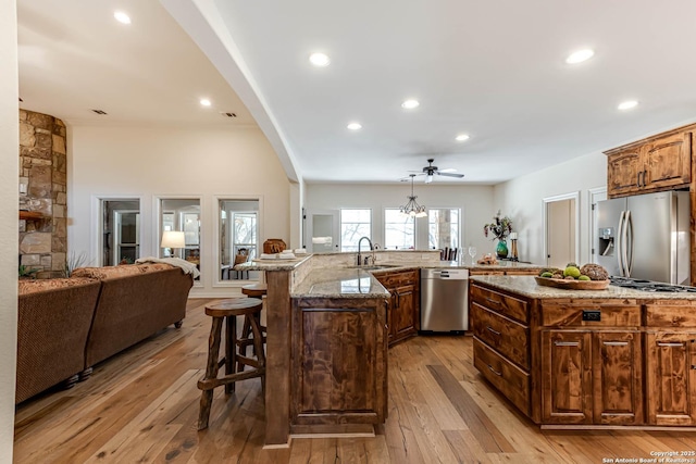 kitchen with a kitchen breakfast bar, a large island, appliances with stainless steel finishes, a sink, and light wood finished floors