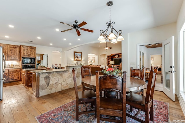 dining area featuring light wood-type flooring, a ceiling fan, arched walkways, and recessed lighting