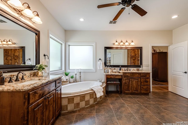 bathroom with two vanities, a ceiling fan, a bath, visible vents, and a sink