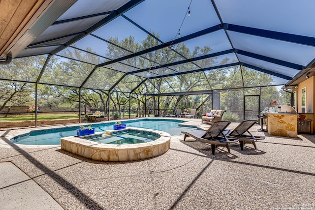 view of swimming pool with an outdoor kitchen, a patio area, a pool with connected hot tub, and glass enclosure