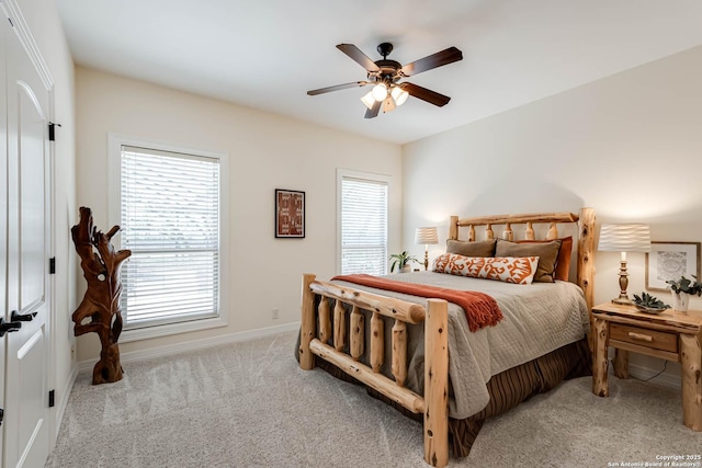carpeted bedroom featuring multiple windows, baseboards, and a ceiling fan