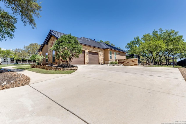 view of front of property featuring a standing seam roof, metal roof, fence, a garage, and driveway