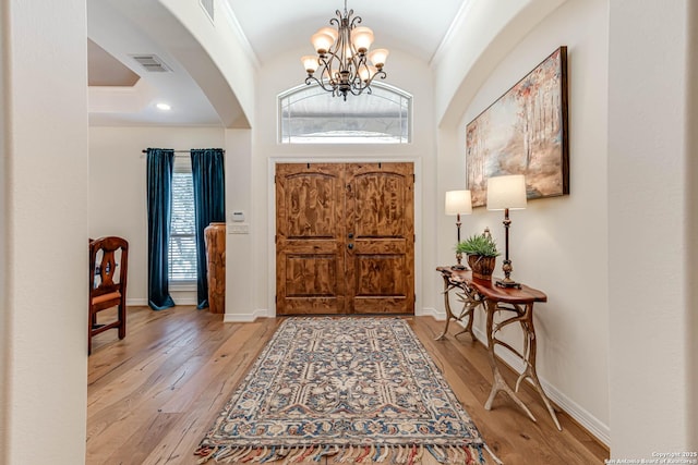 foyer featuring visible vents, baseboards, arched walkways, an inviting chandelier, and wood-type flooring