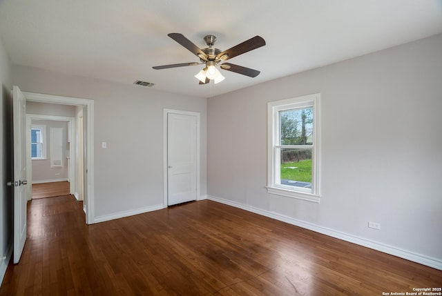 unfurnished bedroom featuring a closet, baseboards, dark wood-style floors, visible vents, and ceiling fan