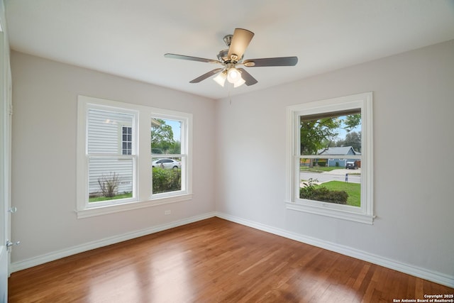 empty room featuring wood finished floors, baseboards, and plenty of natural light