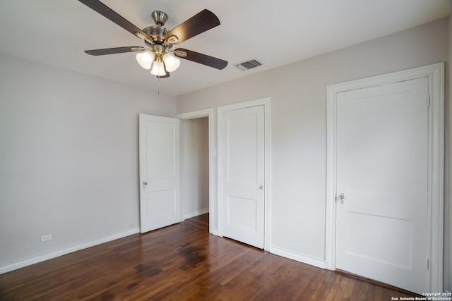 unfurnished bedroom featuring dark wood-style flooring, visible vents, baseboards, and ceiling fan