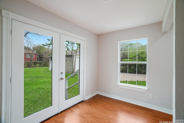 doorway to outside with french doors, light wood-style flooring, and baseboards