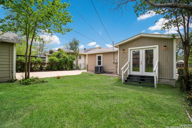 back of property with a patio, french doors, entry steps, central AC, and a lawn