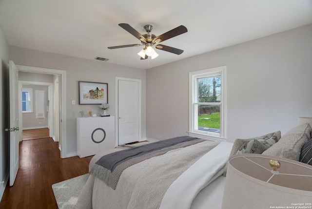 bedroom with dark wood-style flooring, visible vents, baseboards, and a ceiling fan