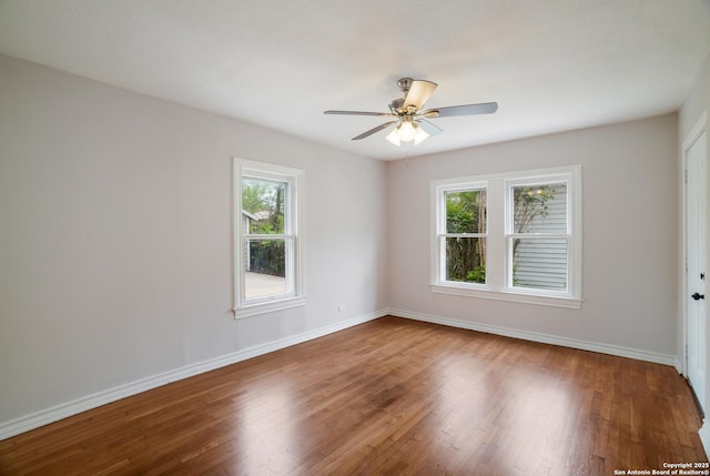empty room featuring a wealth of natural light, baseboards, and wood finished floors