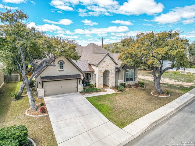 french provincial home featuring a standing seam roof, a garage, stone siding, and metal roof