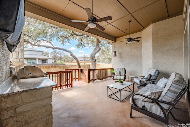 view of patio / terrace with ceiling fan, area for grilling, fence, an outdoor hangout area, and an outdoor kitchen