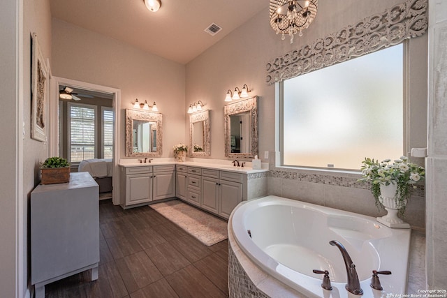 full bathroom featuring double vanity, a bath, visible vents, lofted ceiling, and a sink