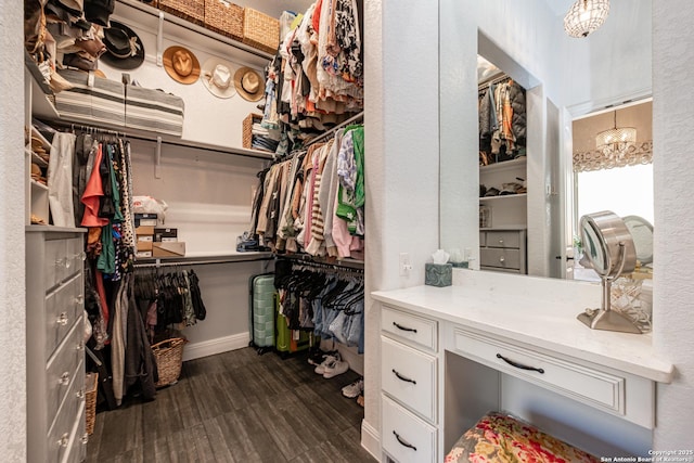 spacious closet featuring a chandelier and dark wood-style flooring