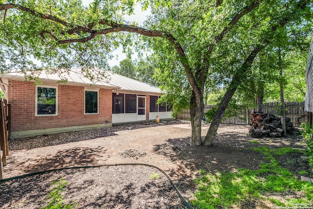 10 Oakwell Farms Pkwy, San Antonio, TX 78218 - rear view of property featuring brick siding, a fenced backyard, a standing seam roof, metal roof, and a sunroom