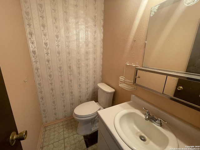 bathroom with vanity, baseboards, and toilet