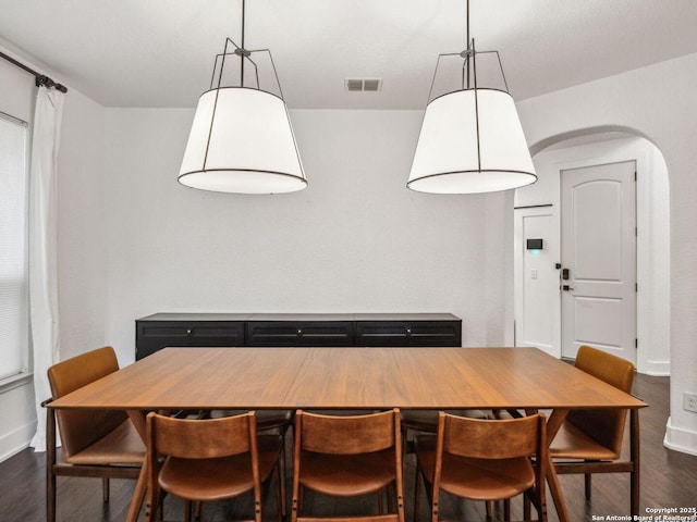 dining area featuring arched walkways, dark wood-style flooring, baseboards, and visible vents