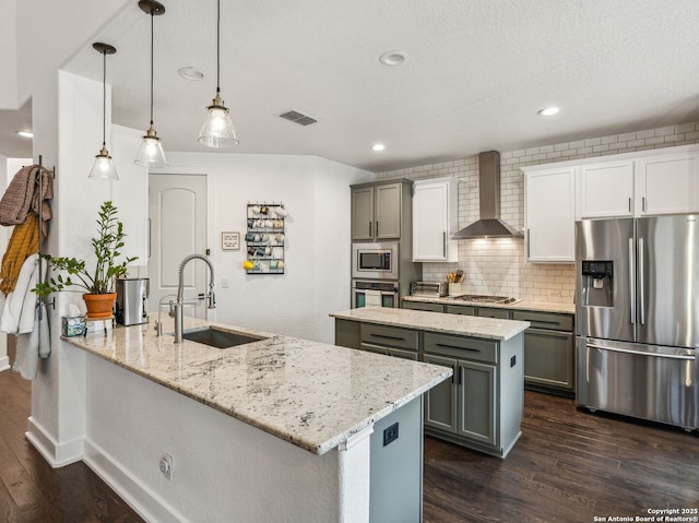 kitchen featuring gray cabinets, visible vents, wall chimney exhaust hood, stainless steel appliances, and a sink
