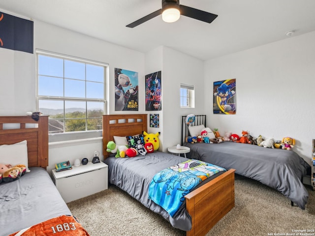 carpeted bedroom with a ceiling fan and multiple windows